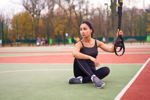 Girl athlete training using trx sportground Mixed race young adult woman workout suspension system Healthy lifestyle Stretching outdoors playground. Make your body machine