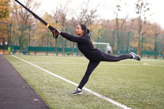 Girl athlete training using trx sportground Mixed race young adult woman workout suspension system Healthy lifestyle Stretching outdoors playground. Make your body machine