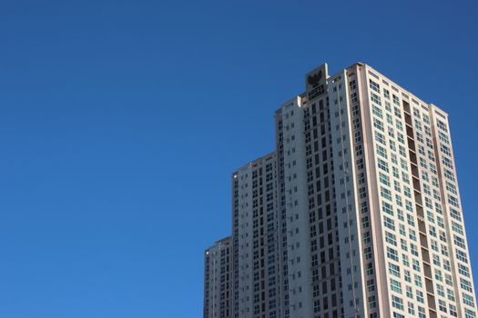 The wide-angle view of a skyscraper commercial building with blue sky on sunny day.