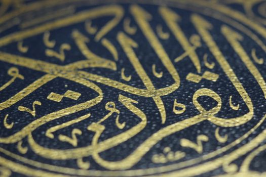 Closeup shot of Islamic Book Quran with golden arabic calligraphy that means Al-Quran, the Holy Quran