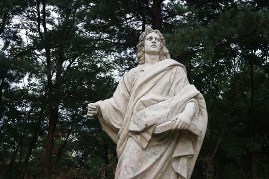 CHUNCHEON, SOUTH KOREA- October-03, 2020: Statue of a man holding a book in one hand. White marble statue of man in a public park