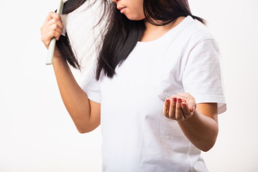 Asian woman weak hair problem her use comb hairbrush brush her hair and showing damaged long loss hair from the brush on hand, studio shot isolated on white background, Medicine health care concept