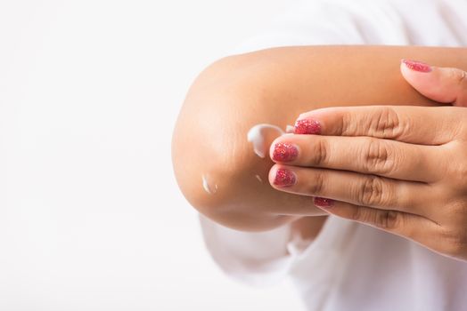 Closeup young Asian woman applies lotion cream on her elbow, studio shot isolated on white background, Healthcare medical and hygiene skin body care concept