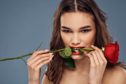 woman with a rose in her hands naked shoulders evening makeup red lips. High quality photo