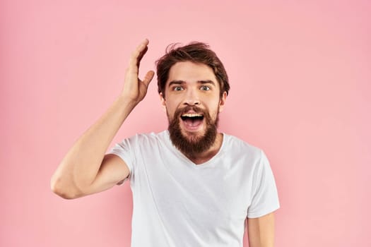 Man in white t-shirt gestures with hands emotions lifestyle cropped view pink background. High quality photo