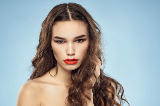 Brunette naked shoulders red lips fashionable hairstyle blue background. High quality photo
