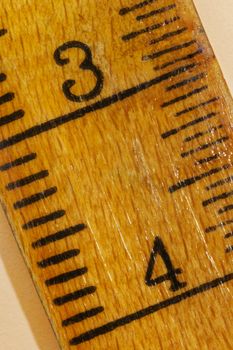 Numbers three and four on a yellow  wooden ruler , black lines along the edges ,the ruler is worn out