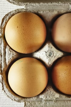 Overhead view of eggs in carton on a white cloth background , beautiful light and shadows on the eggshell