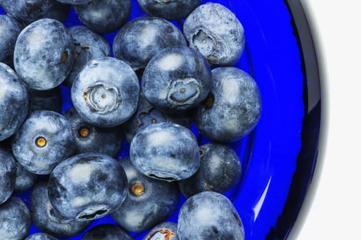 Beautiful blueberries in a blue glass bowl ,the bowl is on a white background ,