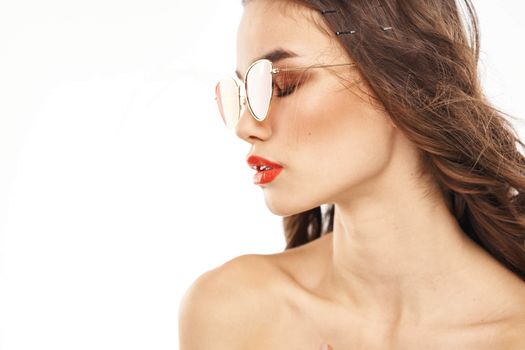 Portrait of brunette woman in sunglasses naked shoulders light background. High quality photo