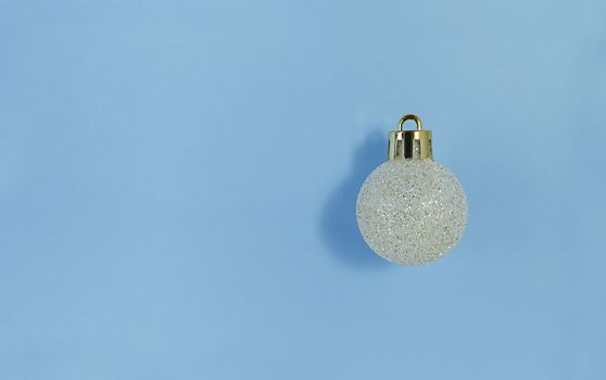 Christmas tree ball on blue paper. Simple flat lay with copy space.