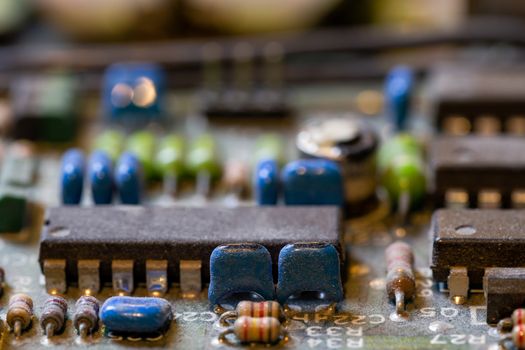 background of old electronic circuit board closeup in dark colors with dust and selective focus