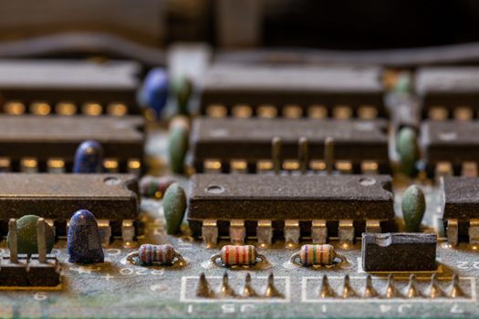 background of old electronic circuit board closeup in dark colors with dust and selective focus