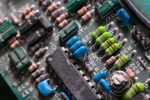 background of old electronic circuit board closeup in dark colors with dust and selective focus