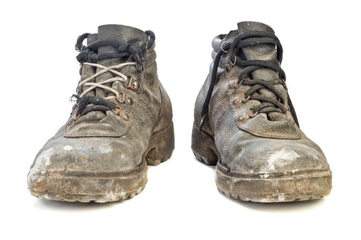 A pair of dirty worn-out old work boots, isolated on white background with shadows