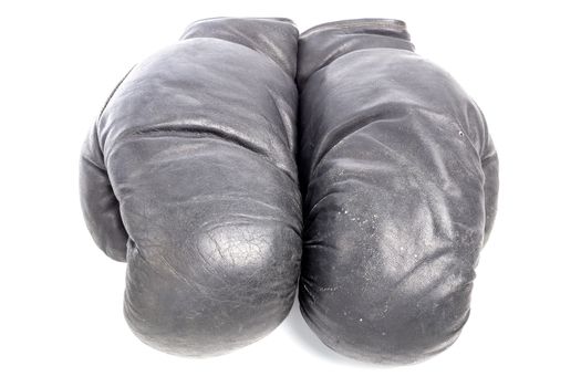 Old black leather boxing gloves isolated on white background with shadows lying on flat surface. Horsehair stuffed.