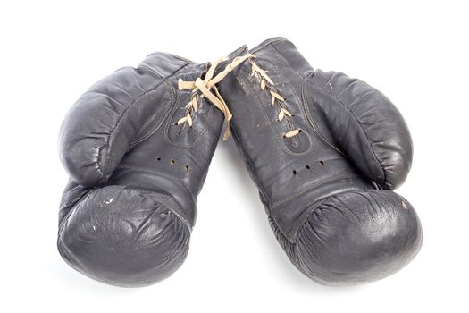 Old black leather boxing gloves isolated on white background with shadows lying on flat surface. Horsehair stuffed.