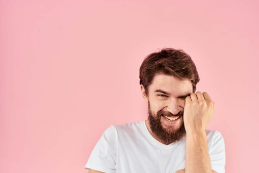 Man in white t-shirt gestures with hands emotions lifestyle cropped view pink background. High quality photo