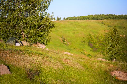 small tent on a hill ridge at daylight summer andscape with selective focus