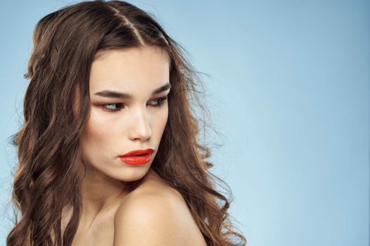 Elegant brunette fashionable hairstyle bright makeup naked shoulders close-up blue background. High quality photo