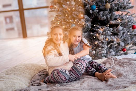 Happy kids having fun and opening presents near christmas tree.