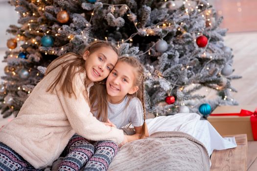 Happy kids having fun and opening presents near christmas tree.