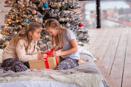 Happy kids having fun and opening presents near christmas tree.