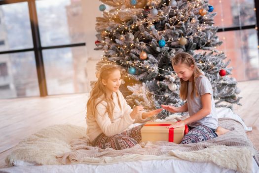 Happy kids having fun and opening presents near christmas tree.