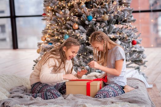 Happy kids having fun and opening presents near christmas tree.