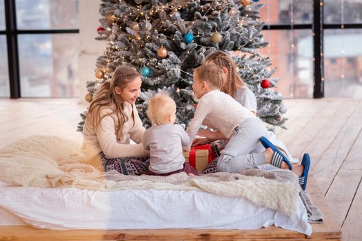 Happy kids having fun and opening presents near christmas tree.