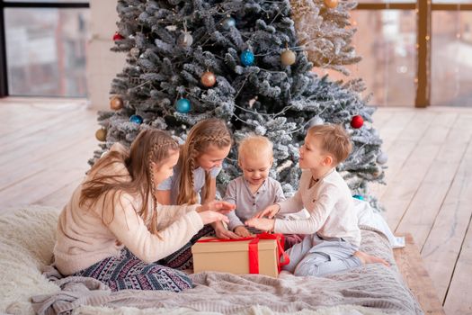 Happy kids having fun and opening presents near christmas tree.