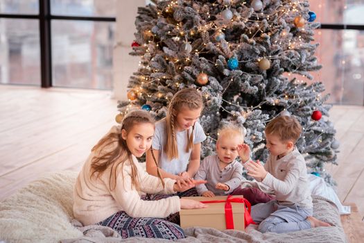 Happy kids having fun and opening presents near christmas tree.