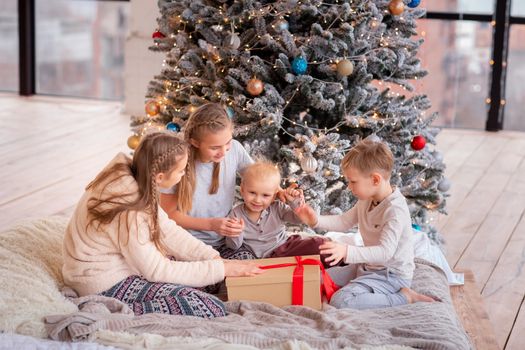 Happy kids having fun and opening presents near christmas tree.