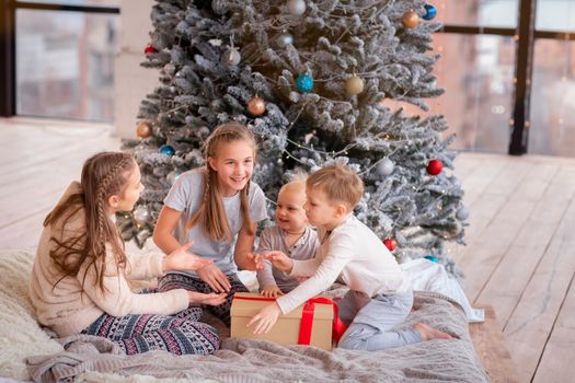 Happy kids having fun and opening presents near christmas tree.