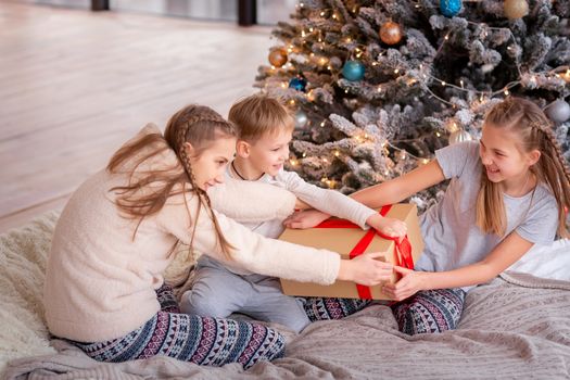 Happy kids having fun and opening presents near christmas tree.