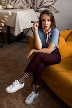 Make-up artist with brushes sitting on the couch in cozy interior