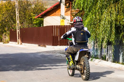 Backview of rider on his enduro motorbike on a village road near Targoviste, Romania, 2020