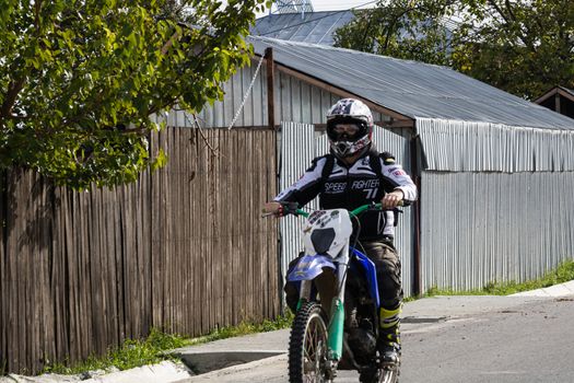 Rider on his enduro motorbike on a village road near Targoviste, Romania, 2020