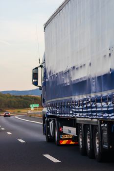 Side view of loaded European truck in motion on asphalt road, transportation and delivery concept. Detail on delivery truck. Bucharest, Romania, 2020