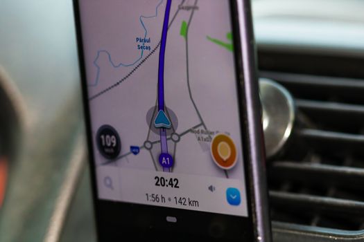 Using waze maps application on smartphone on car dashboard, close up of application. Bucharest, Romania, 2020