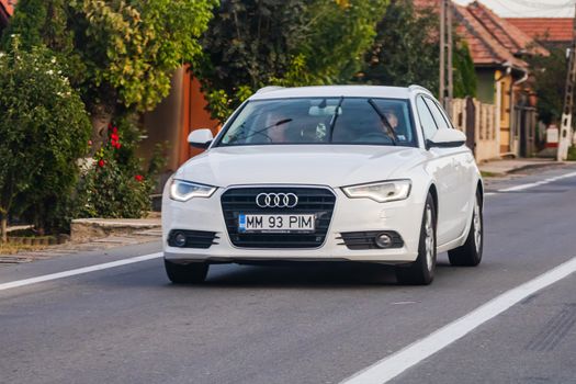 Traveling white Audi car in motion on asphalt road, front view of car on street. Bucharest, Romania, 2020