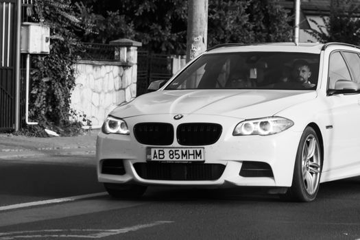 Traveling white BMW car in motion on asphalt road, front view of car on street. Bucharest, Romania, 2020