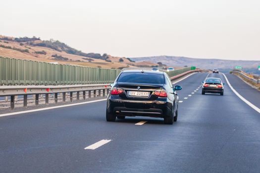 Traveling black car in motion on asphalt road, back view of car on street. Bucharest, Romania, 2020