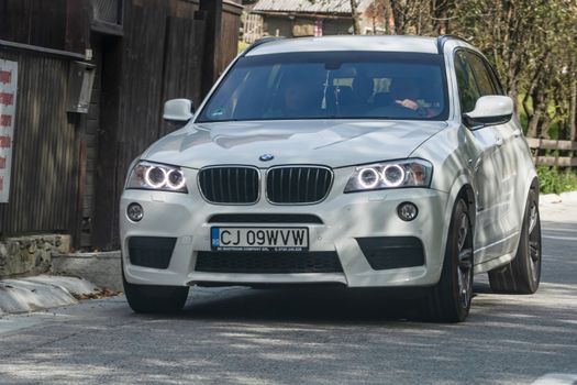 Traveling white BMW car in motion on asphalt road, front view of car on street. Bucharest, Romania, 2020