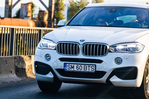 Traveling white BMW car in motion on asphalt road, front view of car on street. Bucharest, Romania, 2020