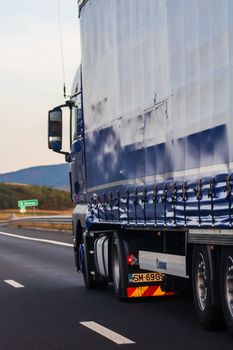 Side view of loaded European truck in motion on asphalt road, transportation and delivery concept. Detail on delivery truck. Bucharest, Romania, 2020