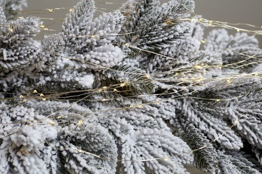 Christmas tree blur garland close-up New year background Decoration with snow and branch of Christmas tree