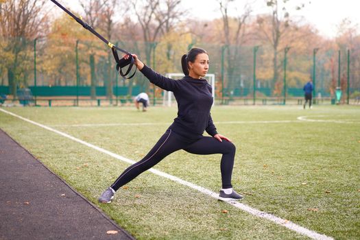 Girl athlete training using trx sportground Mixed race young adult woman workout suspension system Healthy lifestyle Stretching outdoors playground. Make your body machine