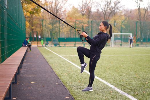 Girl athlete training using trx sportground Mixed race young adult woman workout suspension system Healthy lifestyle Stretching outdoors playground. Make your body machine