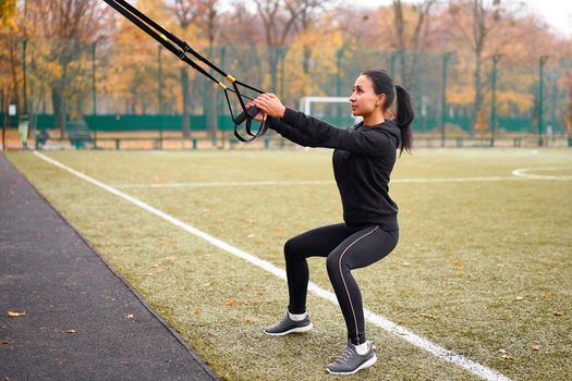 Girl athlete training using trx sportground Mixed race young adult woman workout suspension system Healthy lifestyle Stretching outdoors playground. Make your body machine